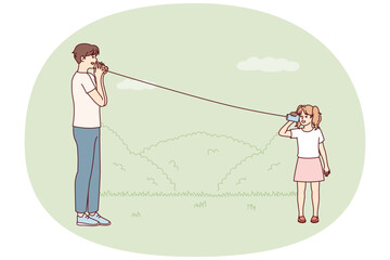 Little girl plays with father in park using cups tied with rope to talk from distance. Man rests with daughter during walk teaches how to use homemade phone from two mugs. Flat vector illustration