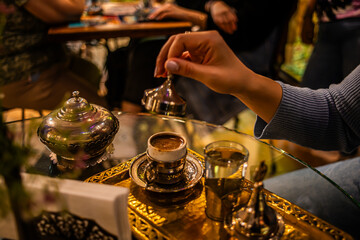 Fototapeta na wymiar A cultural moment unfolds as a woman opens a Turkish coffee cap in a cafe, unveiling the aromatic delight of a brewing experience, capturing the essence of traditional Turkish coffee culture.