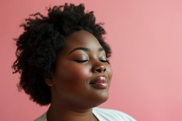 Femininity, body positivity, individuality. Portrait of a positive overweight African American woman carefree with closed eyes on a pink background