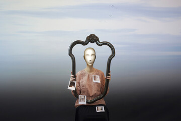surreal woman in frame with mannequin face shows photographs of her face, abstract concept