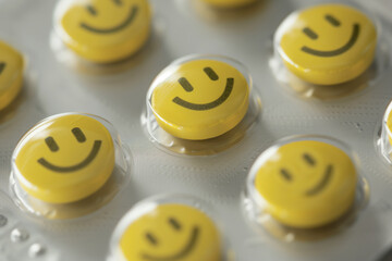 Sealed yellow tablets in the shape of a smiley face close-up, good mood pills