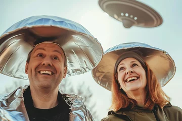 Photo sur Plexiglas UFO man and woman holding metallic hats, exaggerated emotions, futuristic spaceship, ufos in the sky, conspiracy theory concept, sunlight