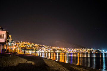 Fototapeta na wymiar A mesmerizing night photo capturing the coastal town's vibrant lights, creating a picturesque urban skyline along the seaside.