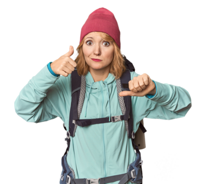 Middle-aged Caucasian woman with hiking gear showing thumbs up and thumbs down, difficult choose concept