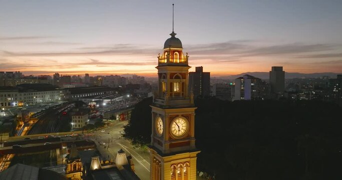 Aerial pan left of Luz Station clock tower illuminated at twilight, Sao Paulo, Brazil