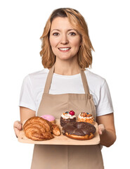 Caucasian middle-aged female baker with sweets tray in studio