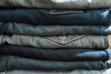 Close up the Stack of jeans in different shades of blue. Folded denim jeans pants, different shades...