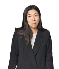 Young Chinese woman in business suit shrugs shoulders and open eyes confused.