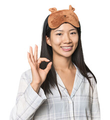 Young Chinese woman in pajamas, mask cheerful and confident showing ok gesture.