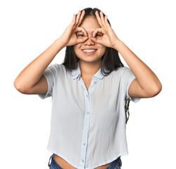 Young chinese woman isolated showing okay sign over eyes