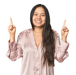 Young chinese woman isolated indicates with both fore fingers up showing a blank space.