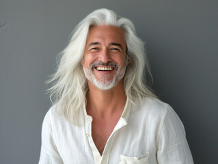 Attraktiver älterer Mann mit langen weißen Haaren lächelnd vor grauem Hintergrund - obrazy, fototapety, plakaty