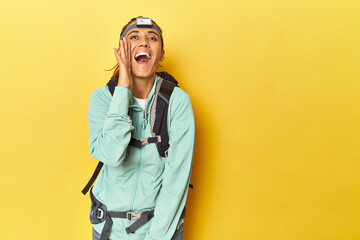 Mountain gear and frontal light on yellow shouting and holding palm near opened mouth.