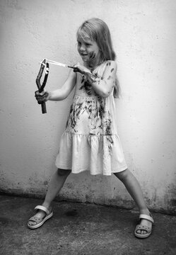 A girl in a dirty dress shoots from a slingshot