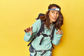 Middle aged hiker woman with backpack and frontal light on yellow