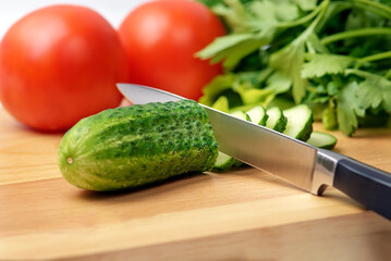 Chopping board with tomato, cucumber, parsley and knife