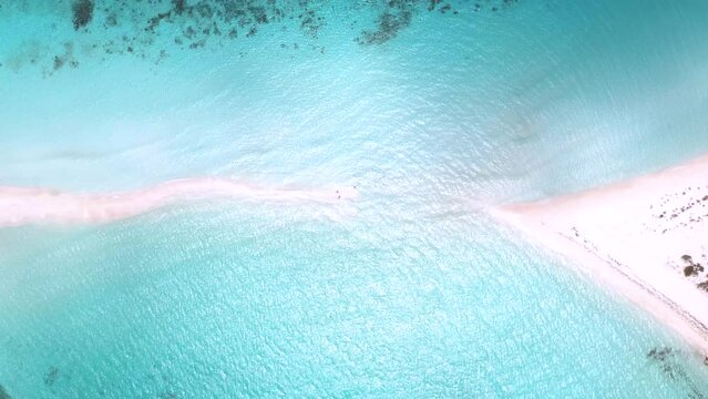Drone zenithal view of ocean waves closing in on sandy isthmus island beach