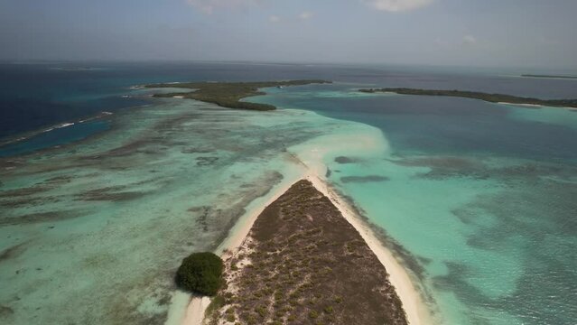 Moody sand flats island with boat anchored over reef by tropical empty shores