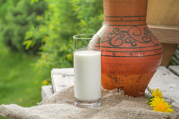 A glass of milk next to a clay jug in patterns. Country style. Summer.