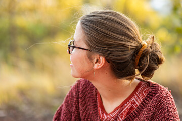 Young woman sitting in nature looking away thinking