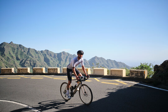 Male cyclist riding gravel bicycle with handlebar bag on road in Anaga Park,Tenerife.Empty mountain road. Sports motivation image.Cycling in beautiful nature.Man cyclist wearing cycling kit and helmet
