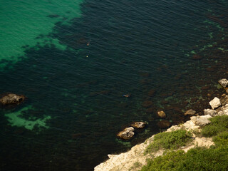 Vibrant Aerial Seascape with Sailboats: Tranquil Azure Waters and Distant Figures Enjoying Sunny Vacation Atmosphere. Top View of Turquoise Sea with Bright Sunlight, Perfect Holiday Getaway Scene.