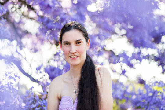 Purple flowers of jacaranda tree and brunette model smiling