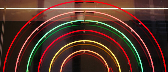 Neon lights forming a rainbow on the window of a shopping center. Abstract background
