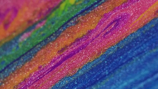 Glitter fluid flow. Paint spill. Color ink wave. Pink blue orange green shimmering metallic texture flow motion on defocused art abstract background.