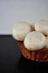 white champignons in a wicker basket on a black background
