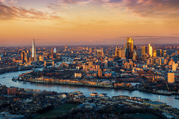 Panoramic, elevated view of the urban London skyline with soft, golden sunlight during sunrise,...