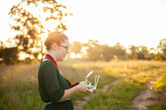 Female RPA pilot using a controller to fly a drone in rural area