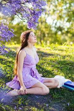 Summer scene of teen girl sitting on grassy slope relaxing outside