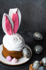 Beautiful stylish still life. Easter cake with rabbit ears, meringue, marshmallows, Easter eggs and willow twigs on a dark background. happy Easter 2024.