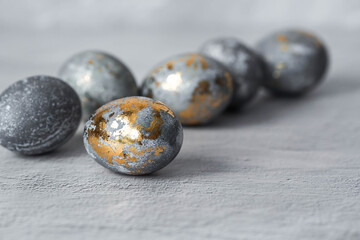 Stylish grey Easter eggs made of marble and concrete with a golden potala on a grey background. Coloring eggs with natural dye karkade tea. . The concept of a happy Easter.