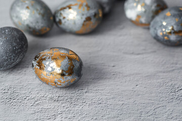 Stylish grey Easter eggs made of marble and concrete with a golden potala on a grey background. Coloring eggs with natural dye karkade tea. . The concept of a happy Easter.