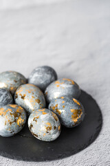 Stylish grey Easter eggs made of marble and concrete with a golden potala on a grey background. Coloring eggs with natural dye karkade tea. . The concept of a happy Easter.