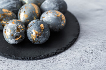 Stylish grey Easter eggs made of marble and concrete with a golden potala on a grey background. Coloring eggs with natural dye karkade tea. . The concept of a happy Easter.