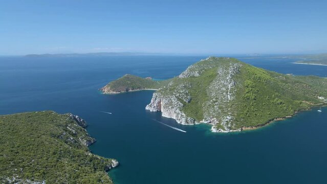 Cinematic rotating up high 4K drone clip over the tropical blue waters of Toroni in Chalkidiki with some boats passing by