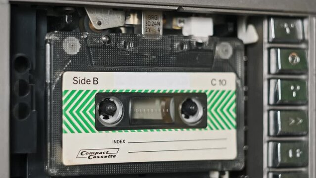 Change audio cassettes in tape recorder playback, close-up. Many different color vintage audio cassettes play in a tape deck. Playing an old tape. Retro tape reels rotate in a deck. 80s, 90s nostalgic