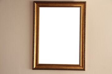 Golden detail frame on beige wall, frame mockup. gold decorated frame hanging on the wall