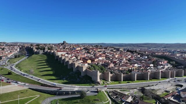 hover flight with drone viewing the medieval walled city of Avila World Heritage Site of Avila focused on the road with cars driving on a sunny morning with a blue sky Avila-Spain
