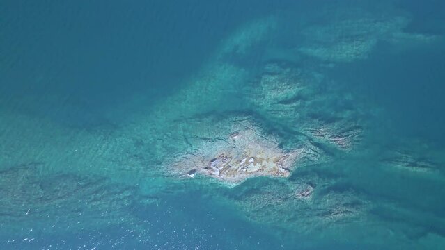 Overhead 4K drone clip over a rock formation in the tropical blue waters of Toroni in Chalkidiki