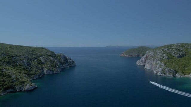Cinematic rotating up high 4K drone clip over the tropical blue waters of Toroni in Chalkidiki with some boats passing by