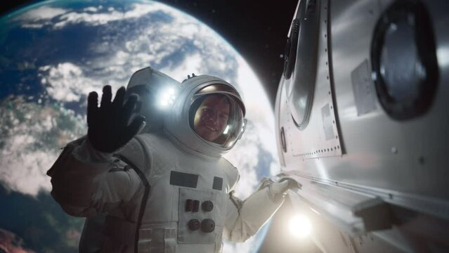 Portrait of an Astronaut Floating Outside a Spaceship with Planet Earth in the Background. Male Waving to the Camera. Professional Spaceman Posing in His Space Suit, Smiling