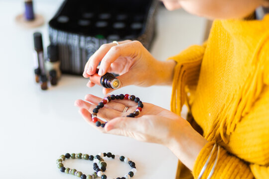 Woman putting essential oils on diffuser bracelet lava stones