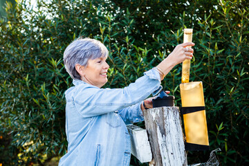 Senior woman checking rain gauge on fence