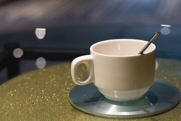 A white ceramic coffee cup mug is placed on a table top.