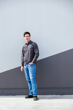 Person standing beside wall in urban area - full length body shot of young man