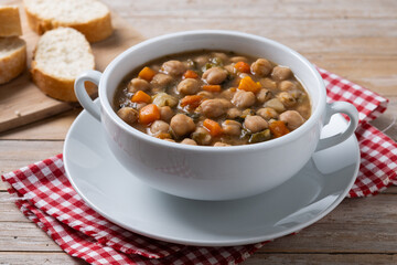 Chickpeas soup with vegetables in bowl on wooden table